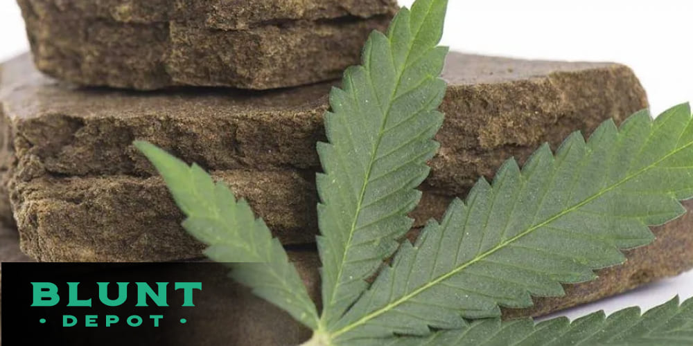 Close-up of clay-like hashish with cannabis leaves in the background