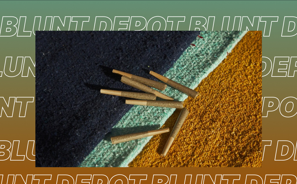 A small pile of pre-rolled cannabis joints with filter tips, resting on a blanket with stripes of blue, teal, and gold.